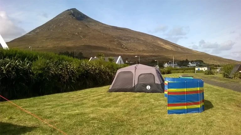 Tent and windbreak set up on grassy field under a mountain, highlighting natural scenery at Mayo Dark Sky Festival.