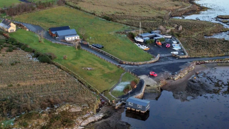 Aerial view of scenic coastal landscape in Ireland for Mayo Dark Sky Festival, featuring green fields and a small harbour.