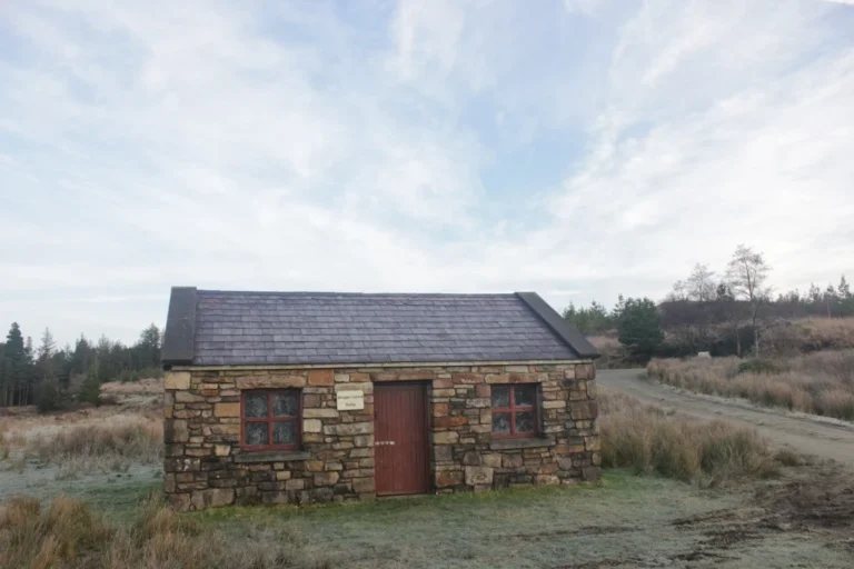 Stone bothy amidst scenic rural landscape at Mayo Dark Sky Festival site, under a bright blue sky.