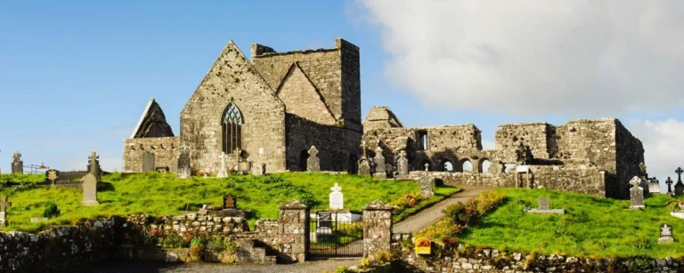 Ancient stone abbey ruins with graveyard in County Mayo, under a bright sky, perfect for Mayo Dark Sky Festival.
