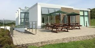 Modern building at Mayo Dark Sky Festival venue with patio seating, framed by lush countryside views.