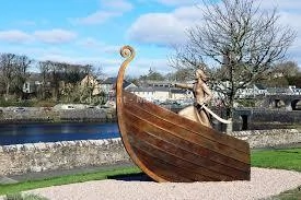 Viking ship sculpture by a river in Mayo, Ireland, under a clear sky at the Mayo Dark Sky Festival.