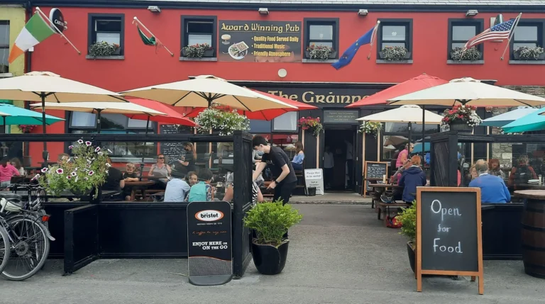 Outdoor dining at award-winning pub with colourful umbrellas and flags in Mulranny, perfect for Mayo Dark Sky Festival visitors.