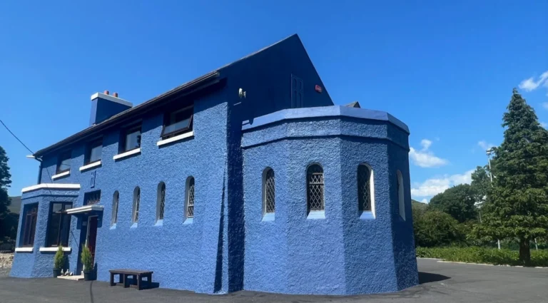 Bright blue building under clear skies at Mayo Dark Sky Festival site, showcasing vibrant architecture and natural beauty.