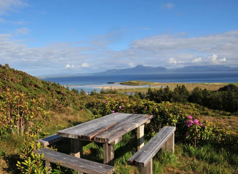 Wooden picnic table overlooking Clew Bay with distant mountains, perfect for Mayo Dark Sky Festival setting.