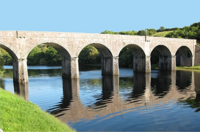 Stone bridge over calm river in County Mayo, perfect backdrop for Mayo Dark Sky Festival events and stargazing activities.