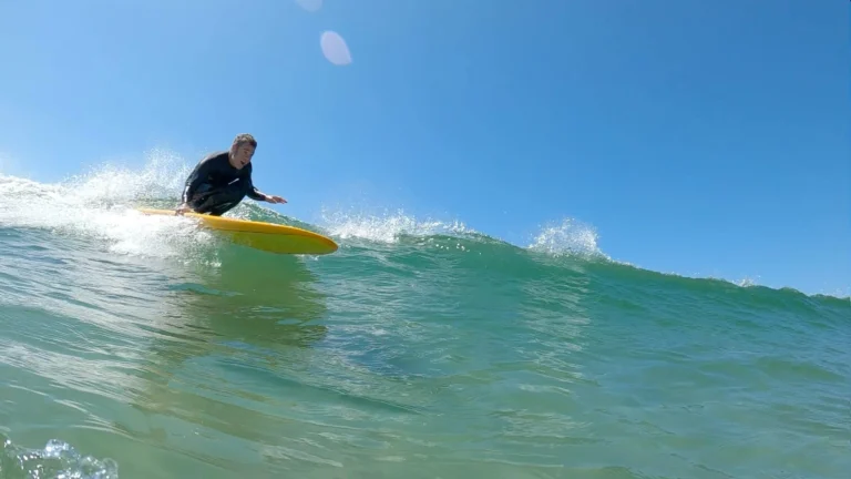 Surfer riding wave, blue skies above, ideal for Mayo Dark Sky Festival outdoor adventure themes.